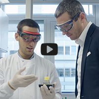 zwei Männer schauen sich ein Stück 3D gedrucktes Glas an